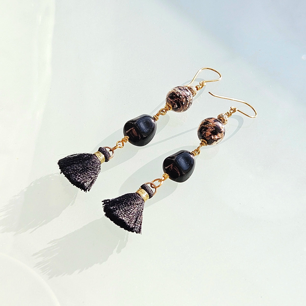 Mustakultaiset korvakorut tupsulla